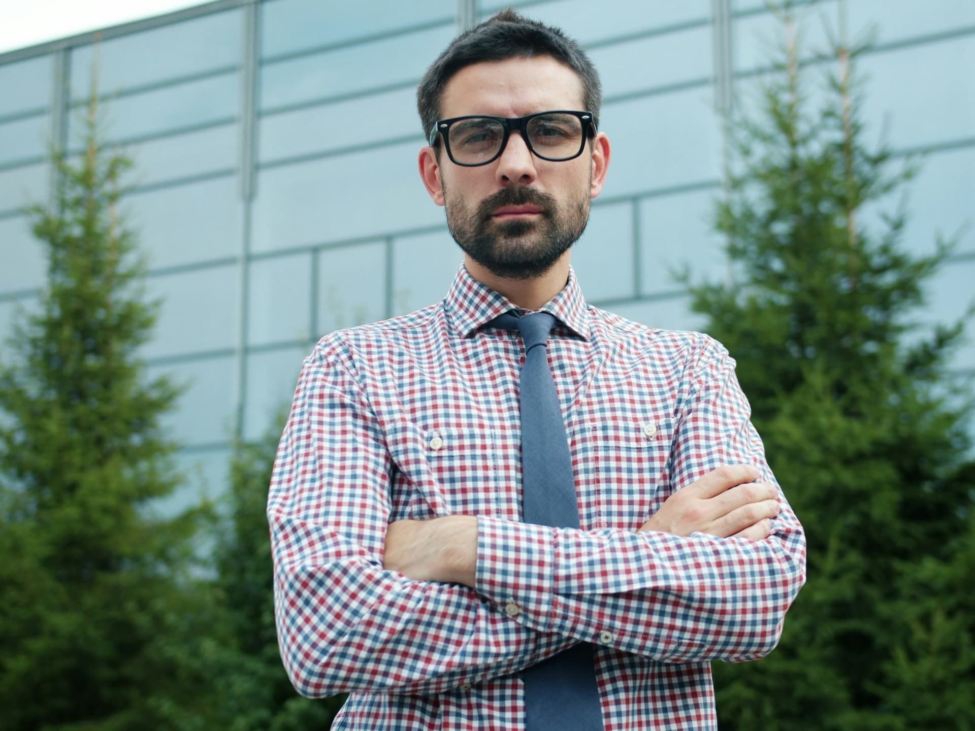 Un antreprenor cu brațele încrucișate în fața clădirii firmei sale